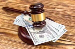 Judge’s gavel and stand with US dollar bills on the wooden table.